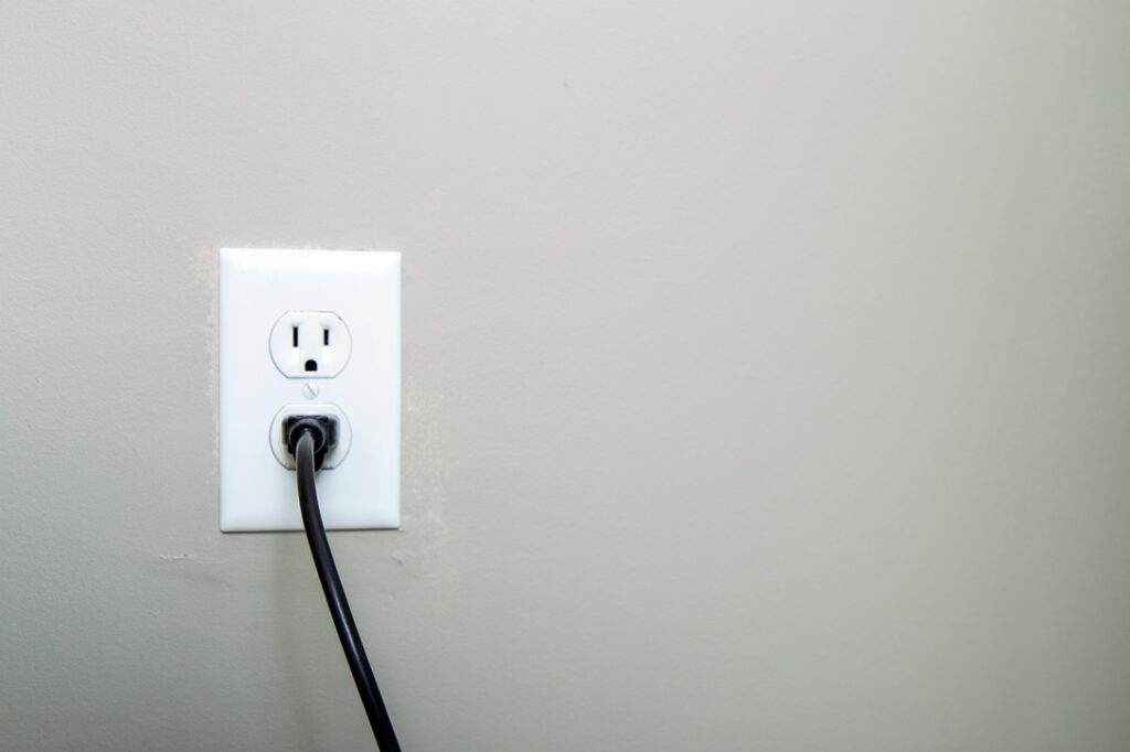 Hardwired vs Plug-In Appliances Black cord plugged into a white outlet
