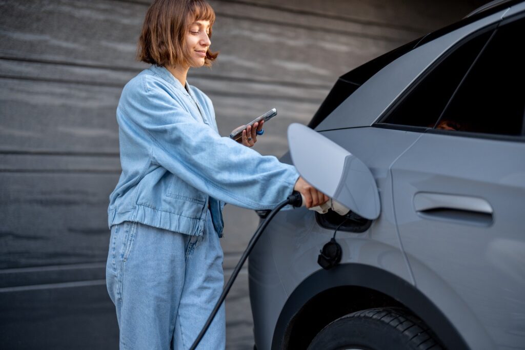 Homeowner charging EV in front of garage