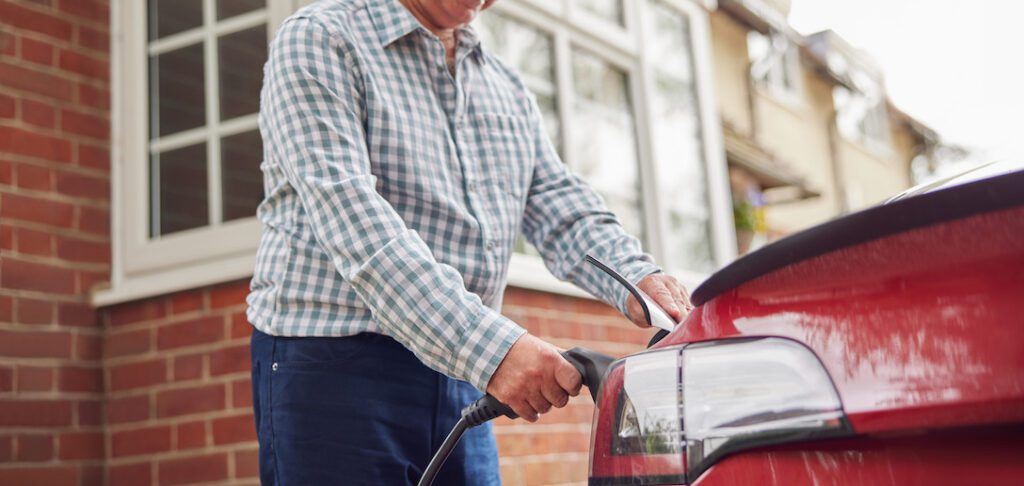 Man charging red electric vehicle outside
